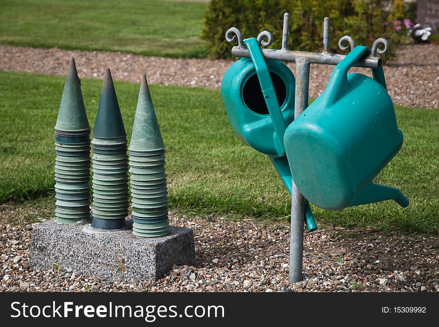 Green plastic watering cans and vases on danish graveyard.