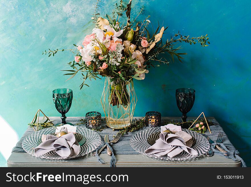Beautiful decorated wedding table with bridal bouquet, flowers, glass, candles