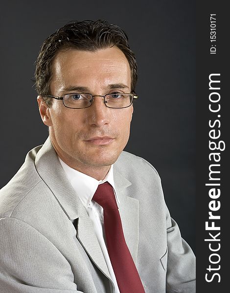 Man in grey jacket with red tie and glasses on grey background