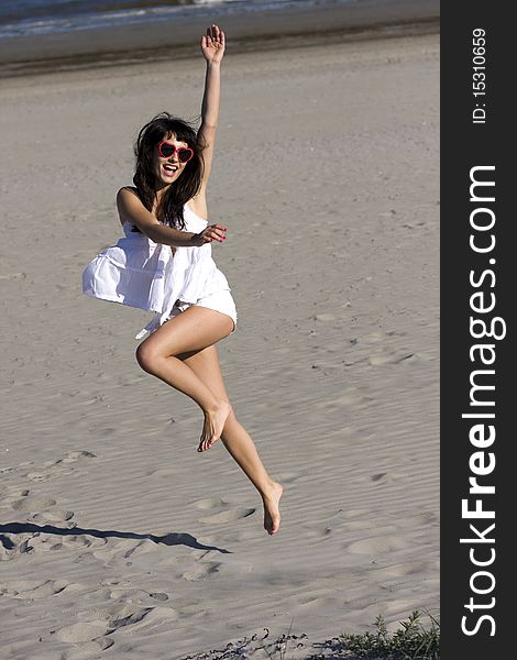 Happy young woman is dancing on the beach