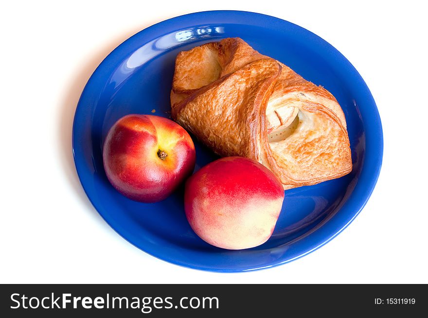 Croissant and red peaches on the blue plate insulation