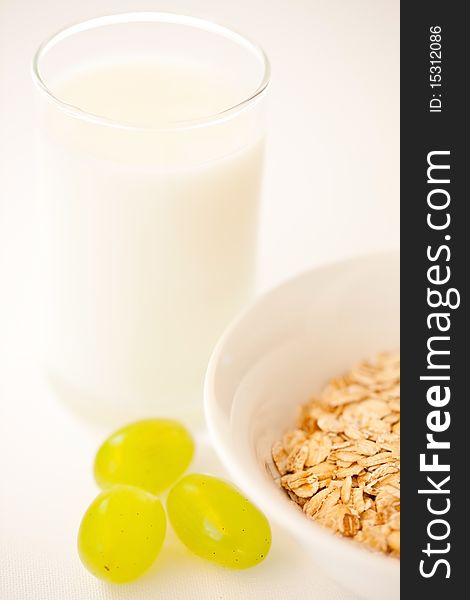 Oats in a bowl with milk in glass on a table. Oats in a bowl with milk in glass on a table.