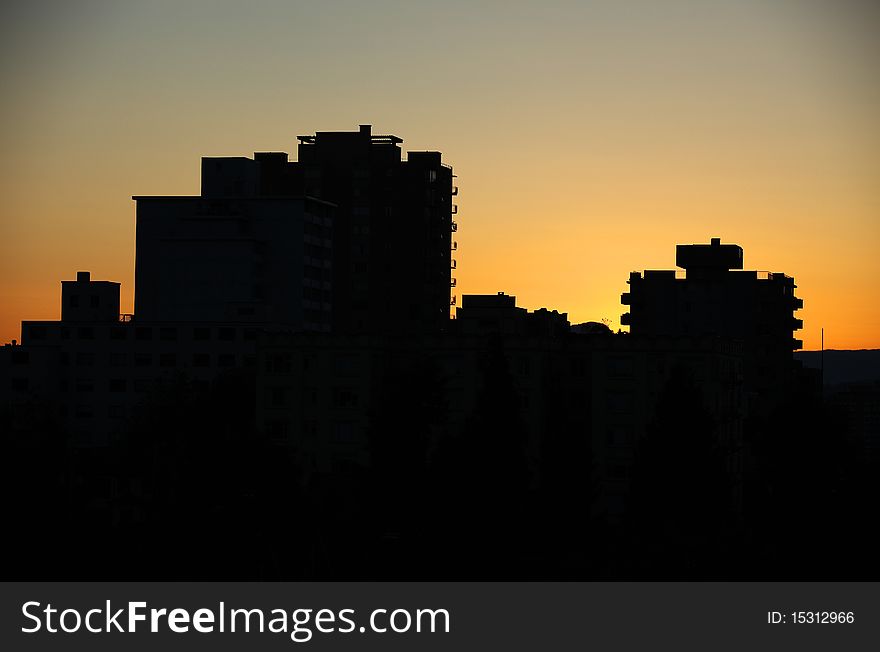 Silhouetted urban skyscrapers against the setting sun. Silhouetted urban skyscrapers against the setting sun