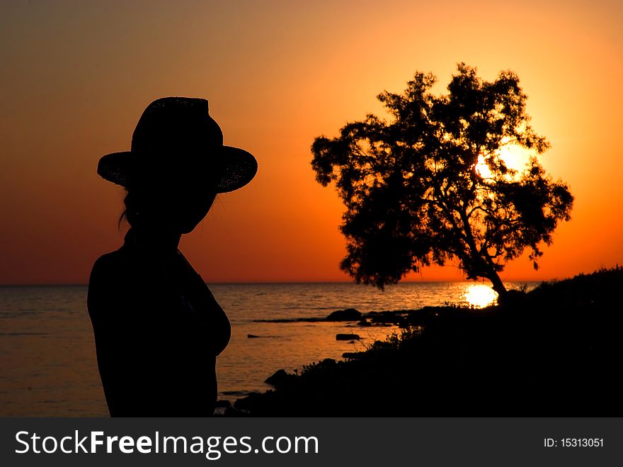 Slender girl silhouette against the sea sunset