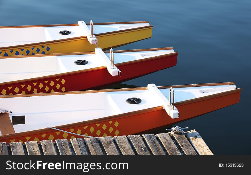 Multi-colored Dragon Boats / paddle boats at a dock. Multi-colored Dragon Boats / paddle boats at a dock