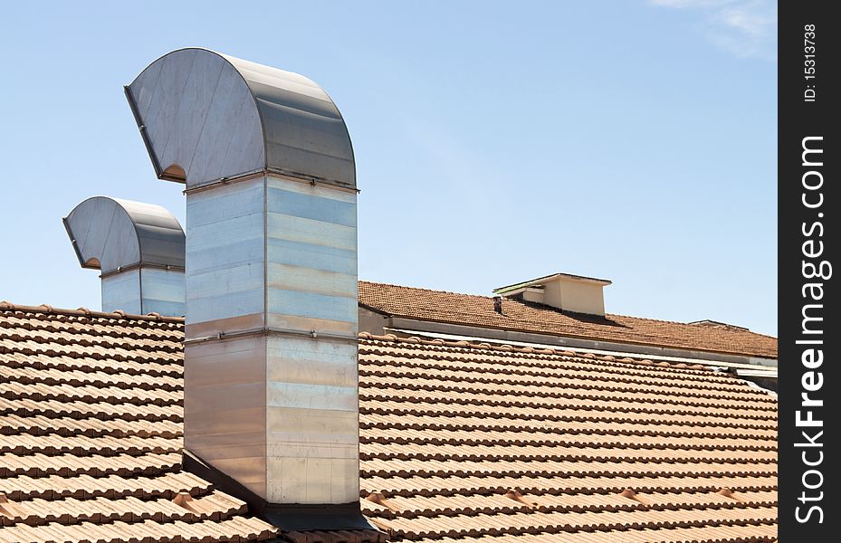 Red tiled roof with chimney on blue sky