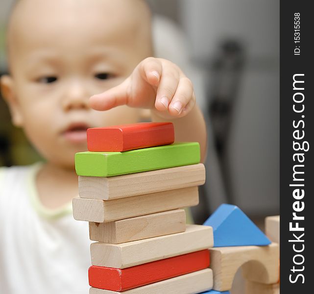 A child is playing with wooden toy blocks in home.