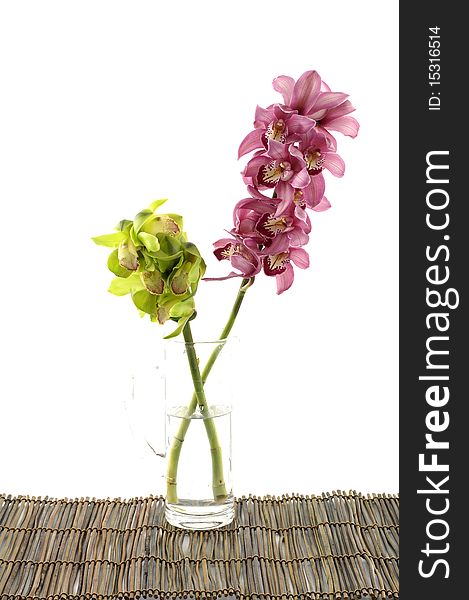 Color orchids in vase on bamboo mat