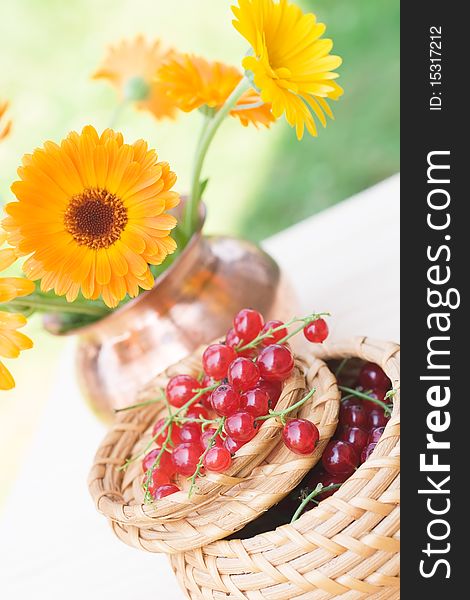 Red currant in a basket and a calendula bouquet