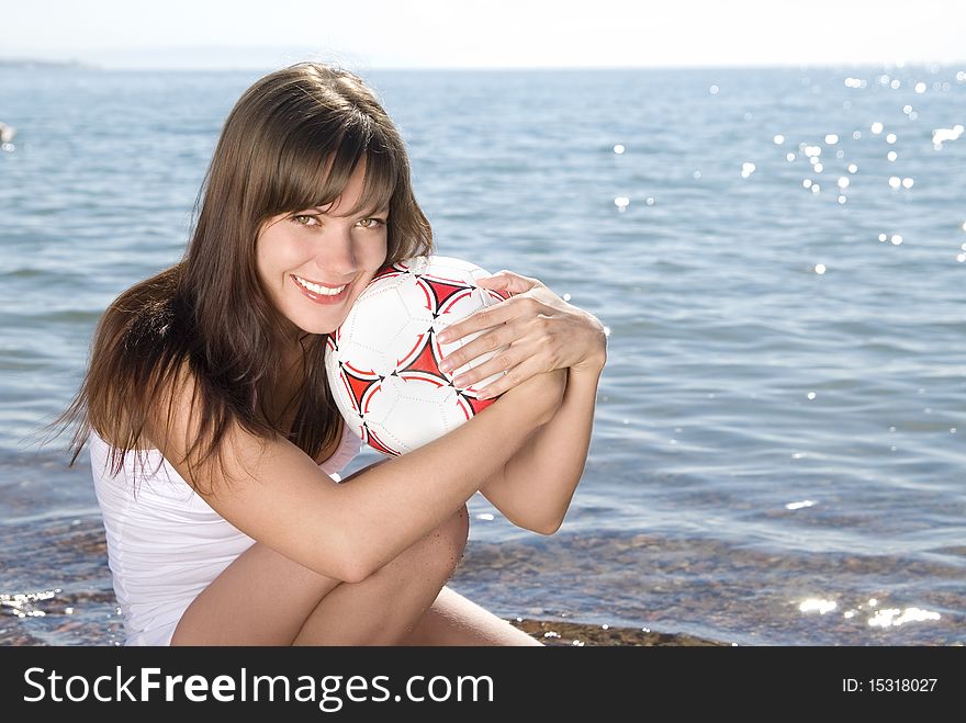 Beautiful young smiling girl in white with a ball on sunny beach. Beautiful young smiling girl in white with a ball on sunny beach