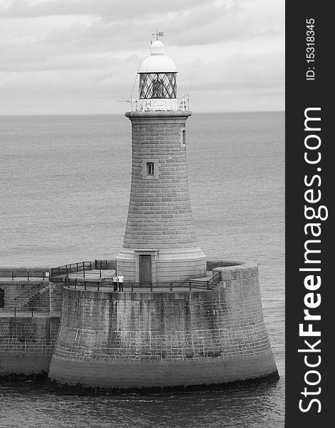 A shot of a lighthouse taken when sailing out of the Newcastle harbor. The horizon lines up perfectly with the roof of the house. A couple is standing at the base. A shot of a lighthouse taken when sailing out of the Newcastle harbor. The horizon lines up perfectly with the roof of the house. A couple is standing at the base.