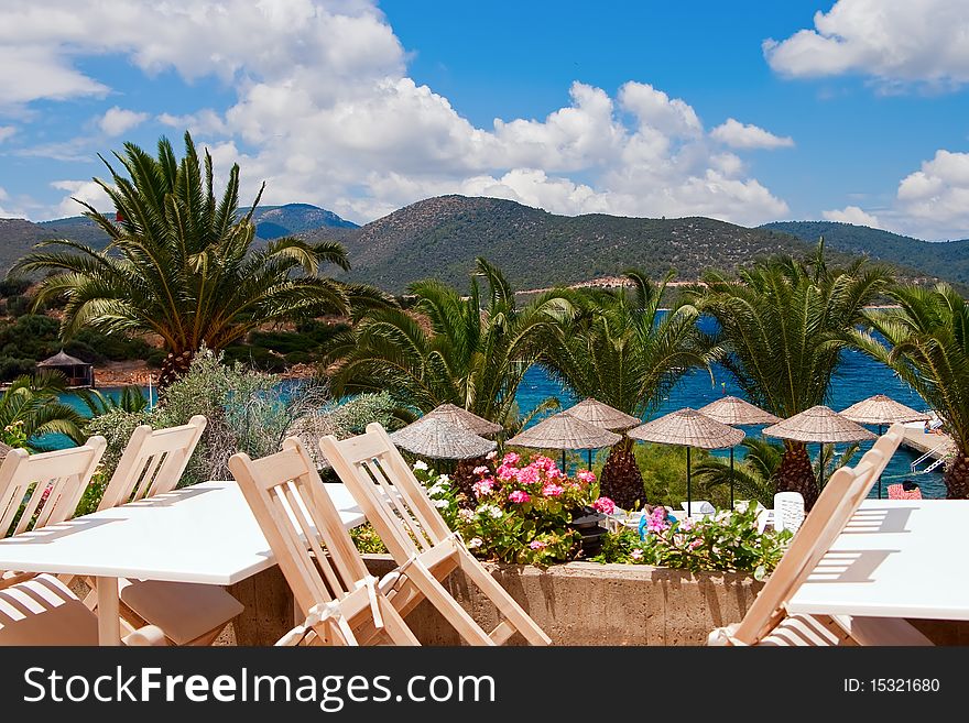 Beautiful view of a restaurant near the sea, with palms and mountains