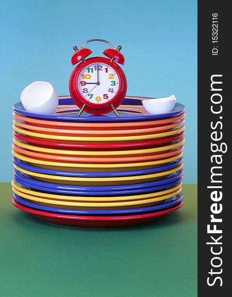 Red alarm clock and egg shell on a plate