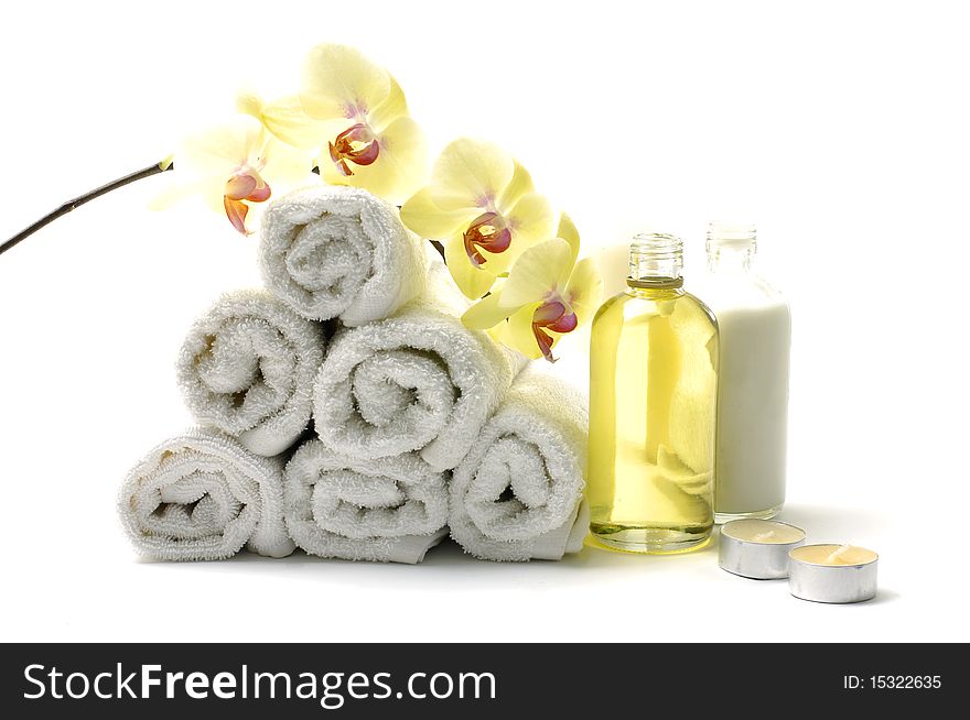 Rolled up white towel, candle, lotion with orchid. Rolled up white towel, candle, lotion with orchid