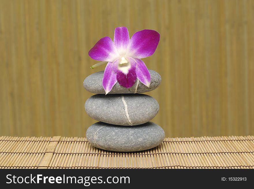 Pink orchid and stones on bamboo mat. Pink orchid and stones on bamboo mat
