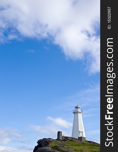 The modern Cape Spear lighthouse against big blue sky and white puffy clouds.