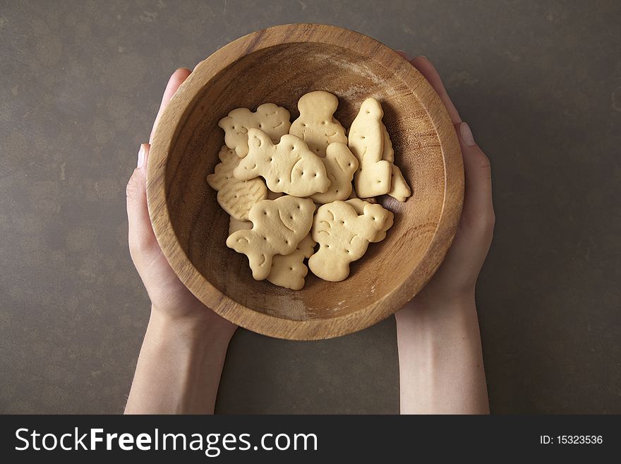 Hands holding fresh biscuit cookies in a wooden plate. Hands holding fresh biscuit cookies in a wooden plate