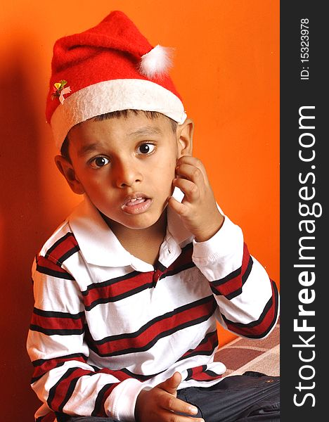 A little Indian boy with a red Christmas cap asking clarification for his doubts. A little Indian boy with a red Christmas cap asking clarification for his doubts.