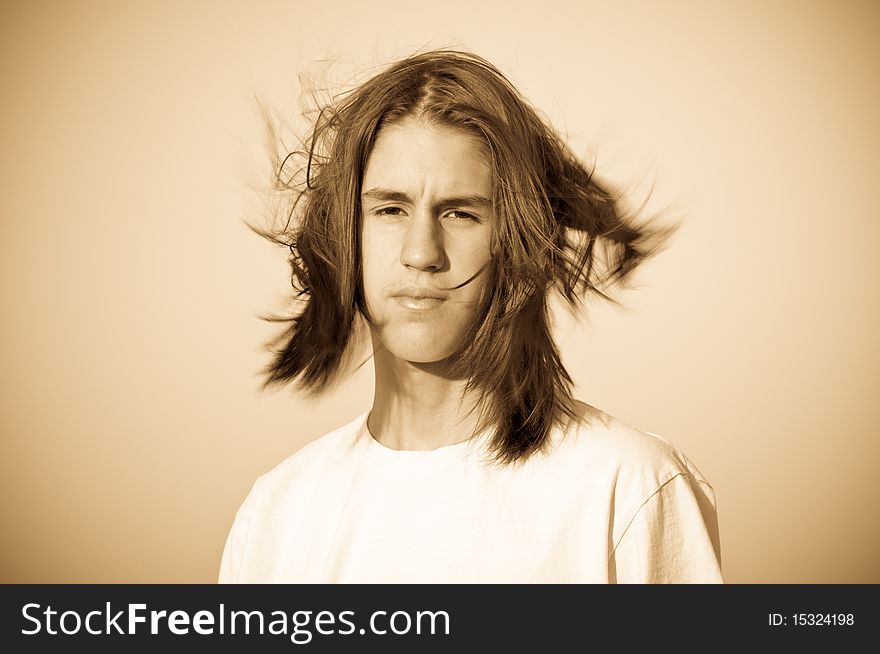 Monochrome portrait of a teenager with disheveled hair, the wind against the sky