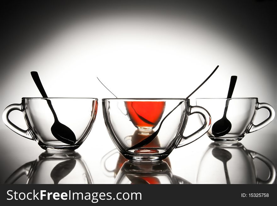 4 glass tea cups with reflection on white and one with tea at 10Mps. 4 glass tea cups with reflection on white and one with tea at 10Mps