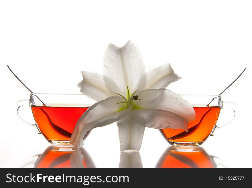 2 glass tea cups and flower with reflection on white at 10Mps. 2 glass tea cups and flower with reflection on white at 10Mps