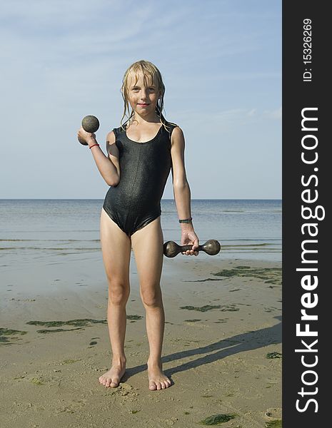 Girl with dumbbells on the beach. Girl with dumbbells on the beach.