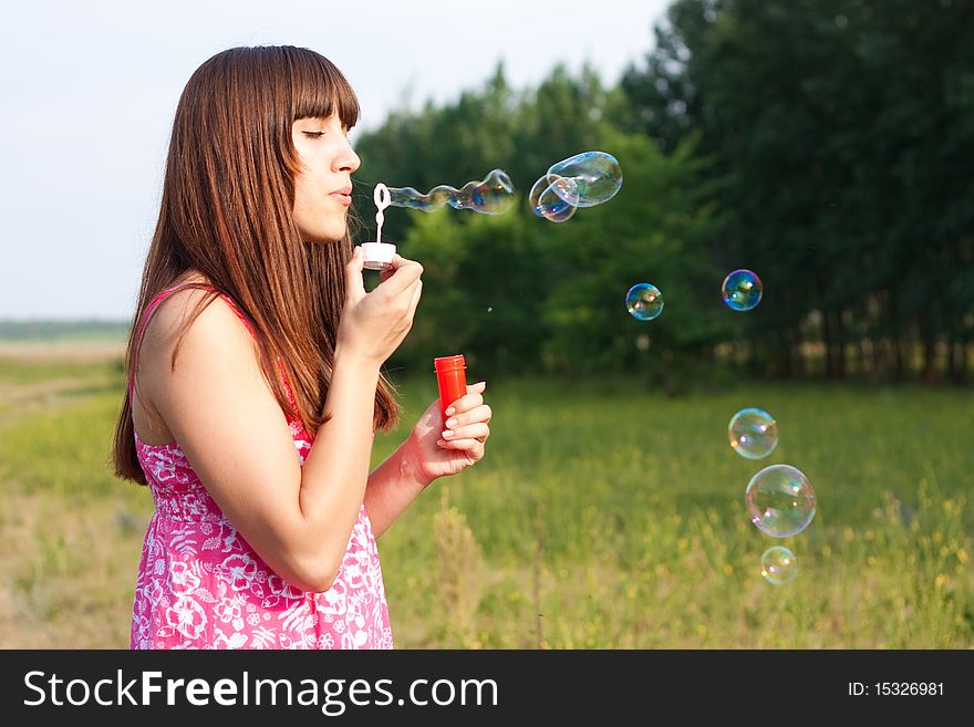 Girl blowing bubbles of soap in sunny weather. Girl blowing bubbles of soap in sunny weather