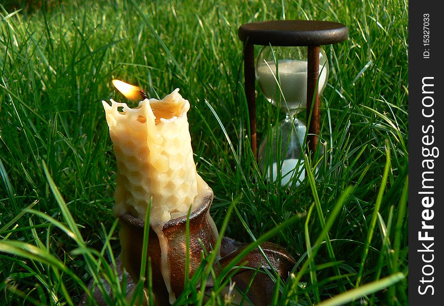 Time is burning scene with sandglass and candle. Time is burning scene with sandglass and candle