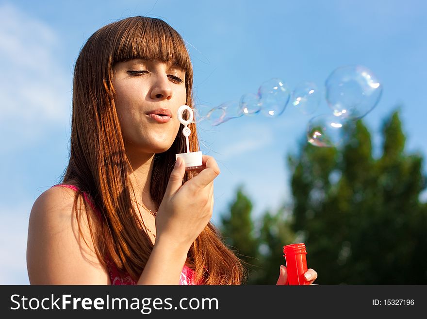 Girl blowing bubbles of soap in sunny weather. Girl blowing bubbles of soap in sunny weather