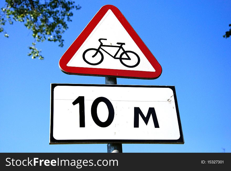 Road cycle sign with informational plate and blue sky