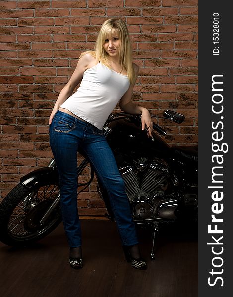 Sexy girl sitting on a motorcycle inside a studio with brick background. Sexy girl sitting on a motorcycle inside a studio with brick background