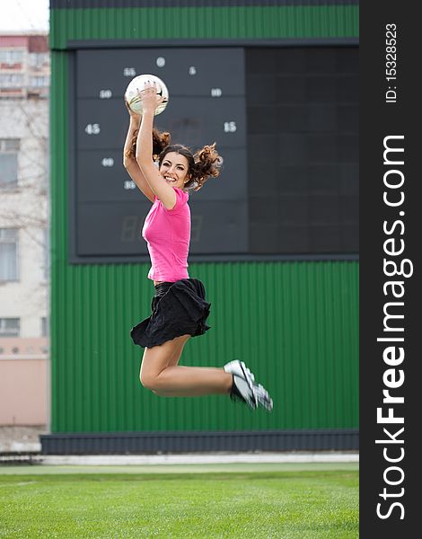 Girl cheerleaders jumping with a soccer ball