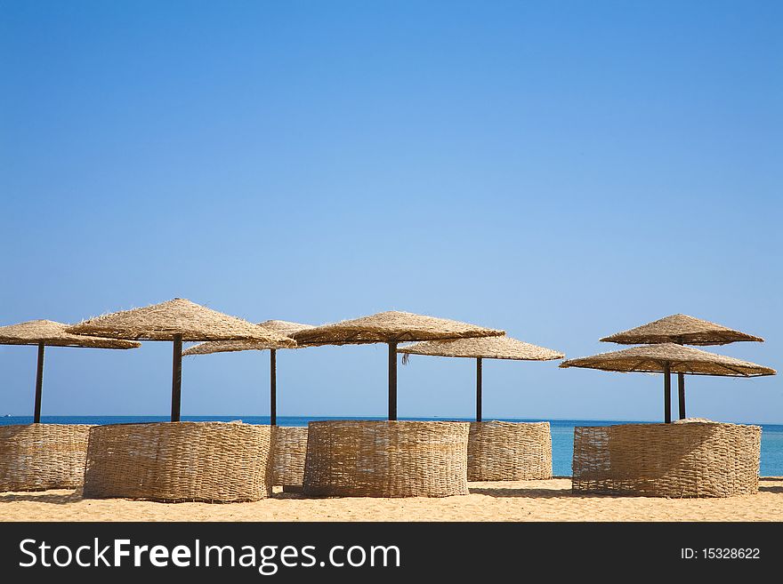 Palm beach umbrellas on a tropical island summer resort. Generic tropical beach