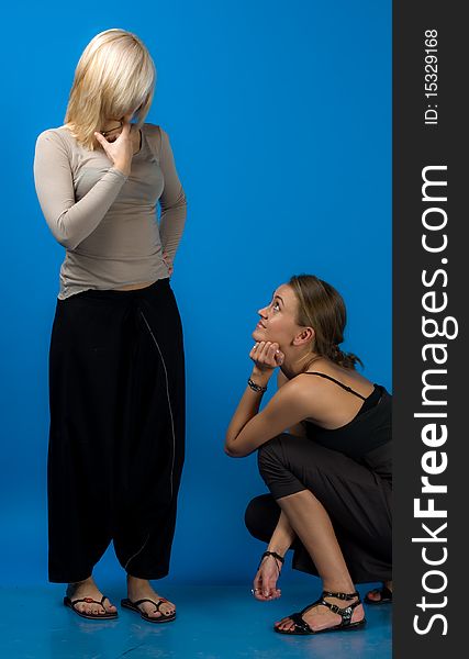 Two beautiful smiling friends girls isolated on blue background. Two beautiful smiling friends girls isolated on blue background.