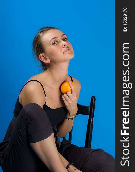 Beautiful young woman holding an orange isolated on blue background. Beautiful young woman holding an orange isolated on blue background