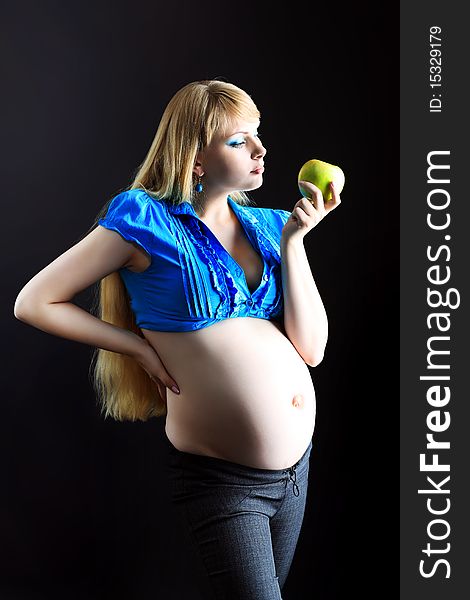 Portrait of a beautiful pregnant woman eating fresh apple. Over black background. Portrait of a beautiful pregnant woman eating fresh apple. Over black background.