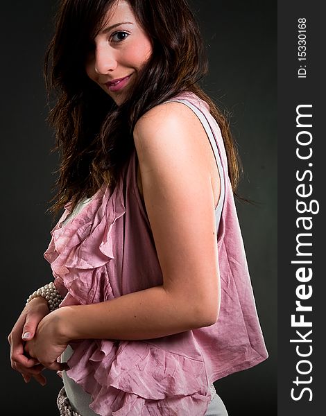 Beautiful teen girl in pink clothes over dark background