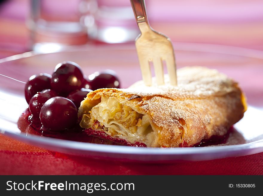 Apple strudel with hot cherries on a plate