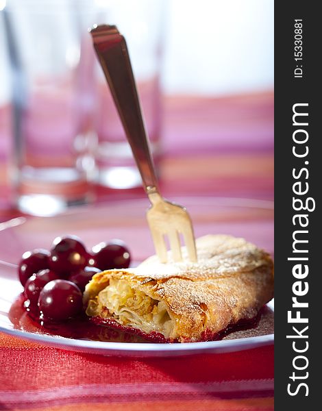 Apple strudel with hot cherries on a plate