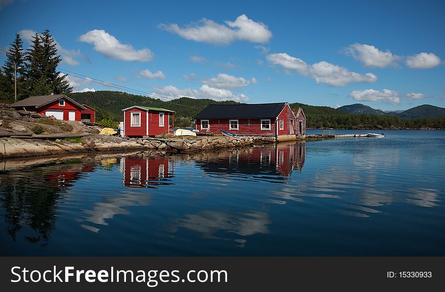 Beautiful nordic red shiphouses, boats and cloud reflections in a water. Shot in sunny beautifull day. Beautiful nordic red shiphouses, boats and cloud reflections in a water. Shot in sunny beautifull day.