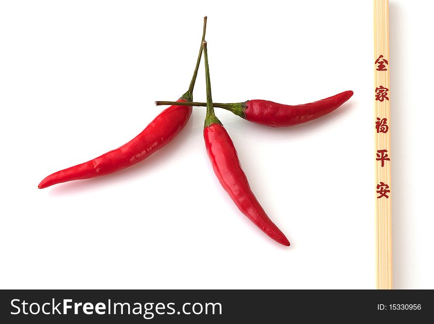 3 red chillis and a chopstick on a white background. 3 red chillis and a chopstick on a white background.