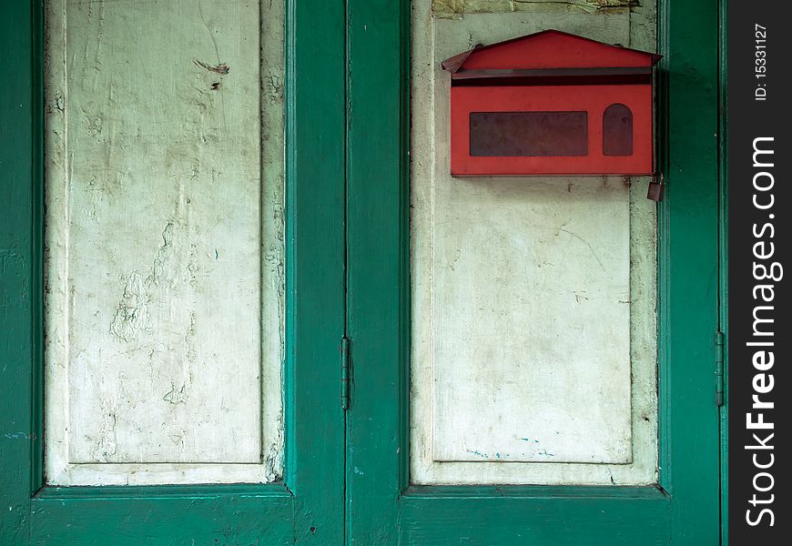 Red mail box on green wood door