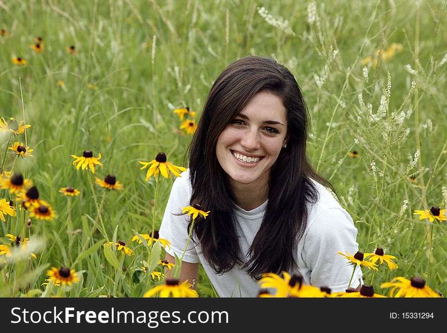 Young smiling woman in green meadow with yellow coneflowers. Young smiling woman in green meadow with yellow coneflowers