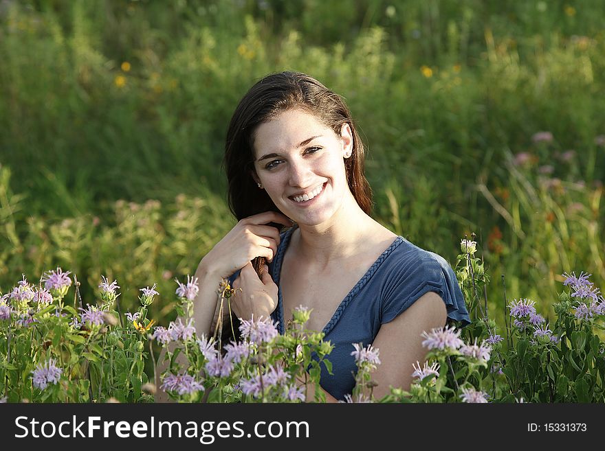 Woman in meadow stroking her hair in late afternoon golden light