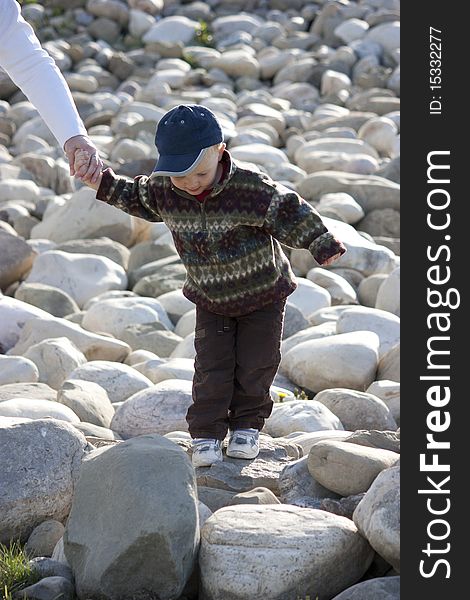 Young boy having fun walking on rocks in the sun. Young boy having fun walking on rocks in the sun.