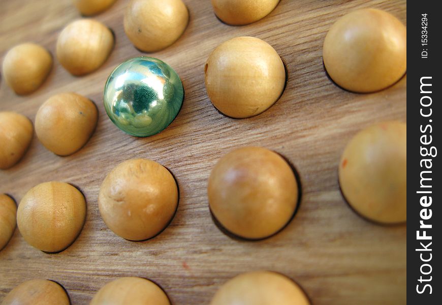 One metal colored sphere among wooden uncolored spheres. One metal colored sphere among wooden uncolored spheres