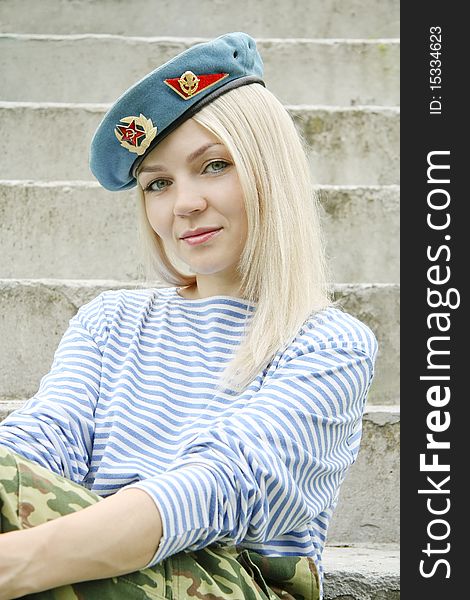 The woman with green eyes in the military form sits on a ladder. The woman with green eyes in the military form sits on a ladder