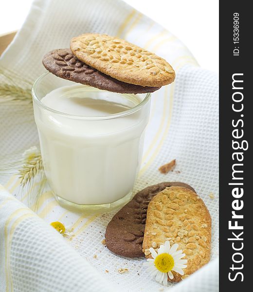 Glass of milk and cookies on light kitchen towel