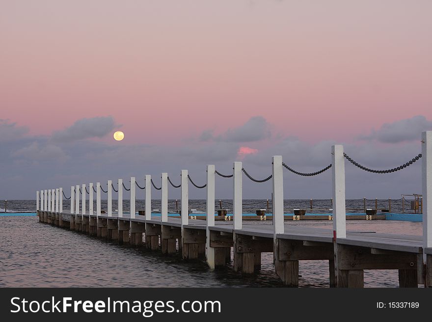 Beautiful coastal sunset as the full moon rises over the ocean. Beautiful coastal sunset as the full moon rises over the ocean