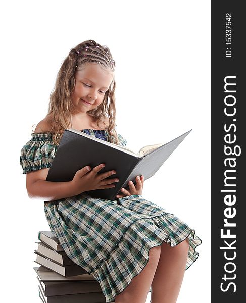 Little girl with pigtails reading a book, isolated on white background, focus on book